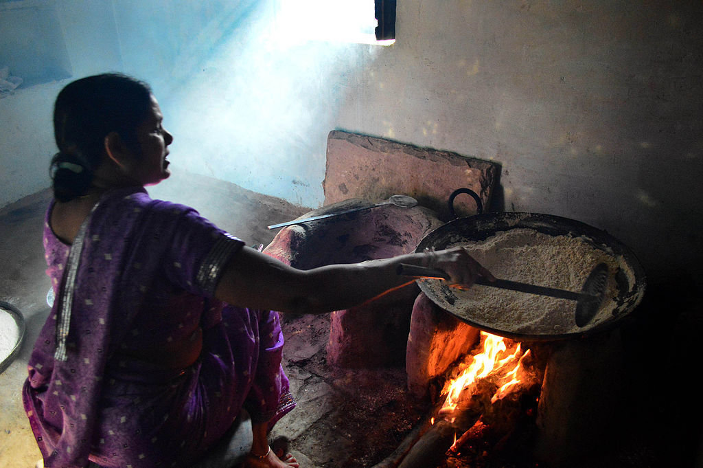 Woman cooking over a traditional wood-fired stove in India