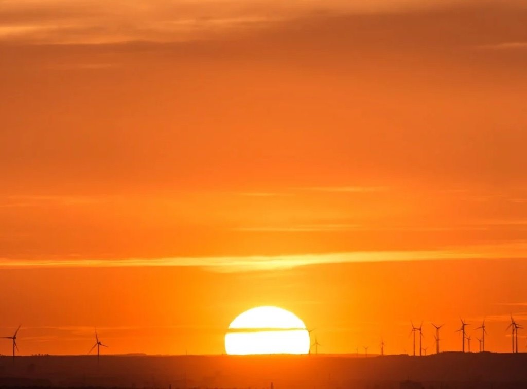 Orange sunset with wind turbines on the horizon